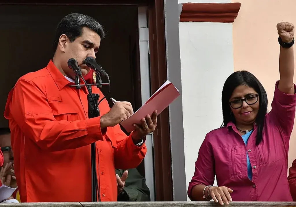 Delcy Rodríguez alza el puño ante Nicolás Maduro.