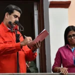 Delcy Rodríguez alza el puño ante Nicolás Maduro.