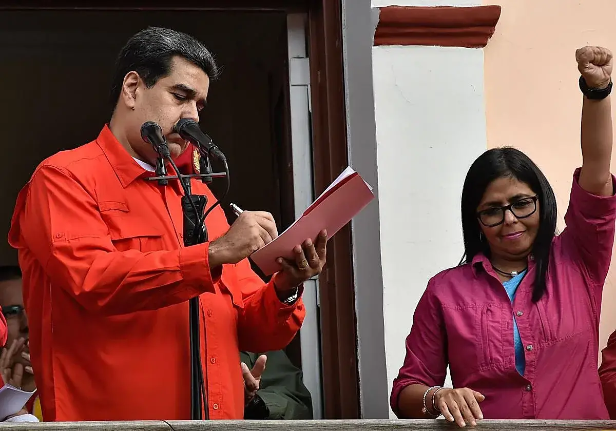 Delcy Rodríguez alza el puño ante Nicolás Maduro.