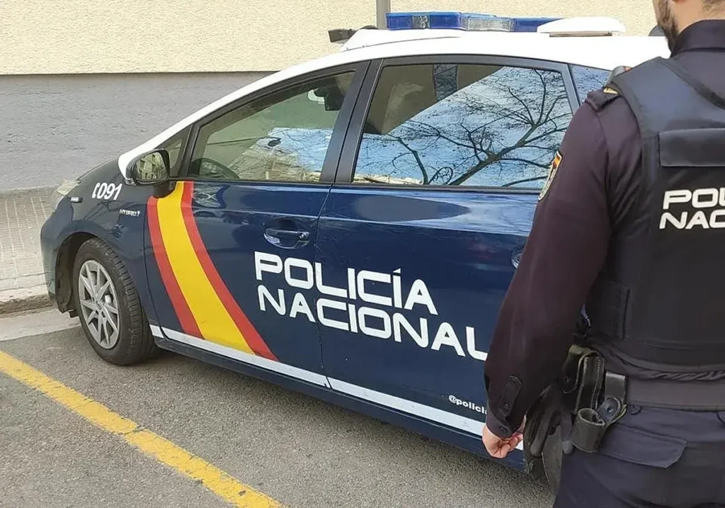 Agente de la Policía Nacional junto a su coche patrulla.