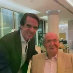 Aznar de pie, tomando la mano de un Juan Carlos I sentado.
