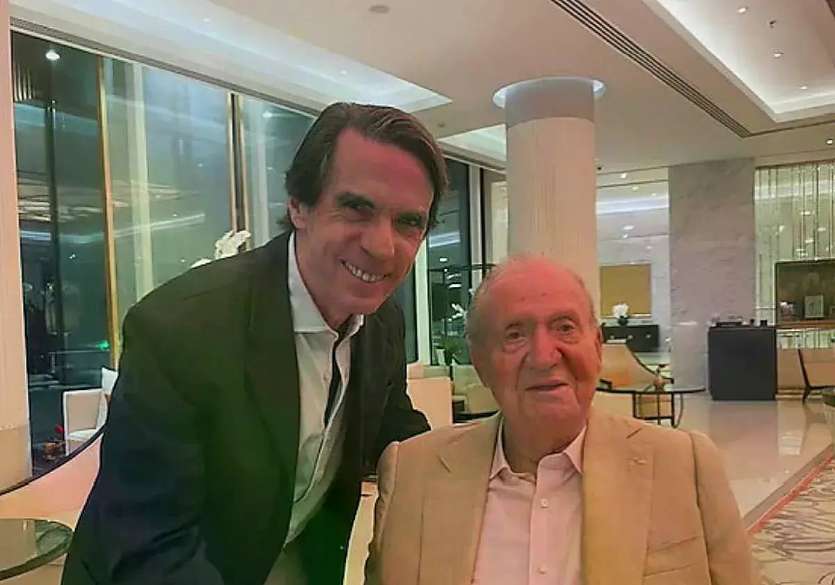 Aznar de pie, tomando la mano de un Juan Carlos I sentado.