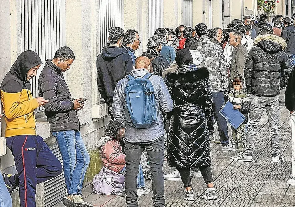 Inmigrantes hacen cola a las puertas de la administración.