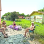 Vecinos toman el sol en medio de construcciones derruidas. (Paloma Ucha)